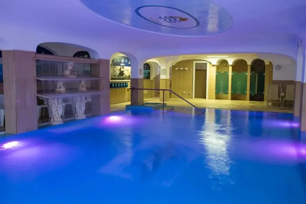 Piscina coperta con illuminazione blu e viola e decorazioni in stile classico