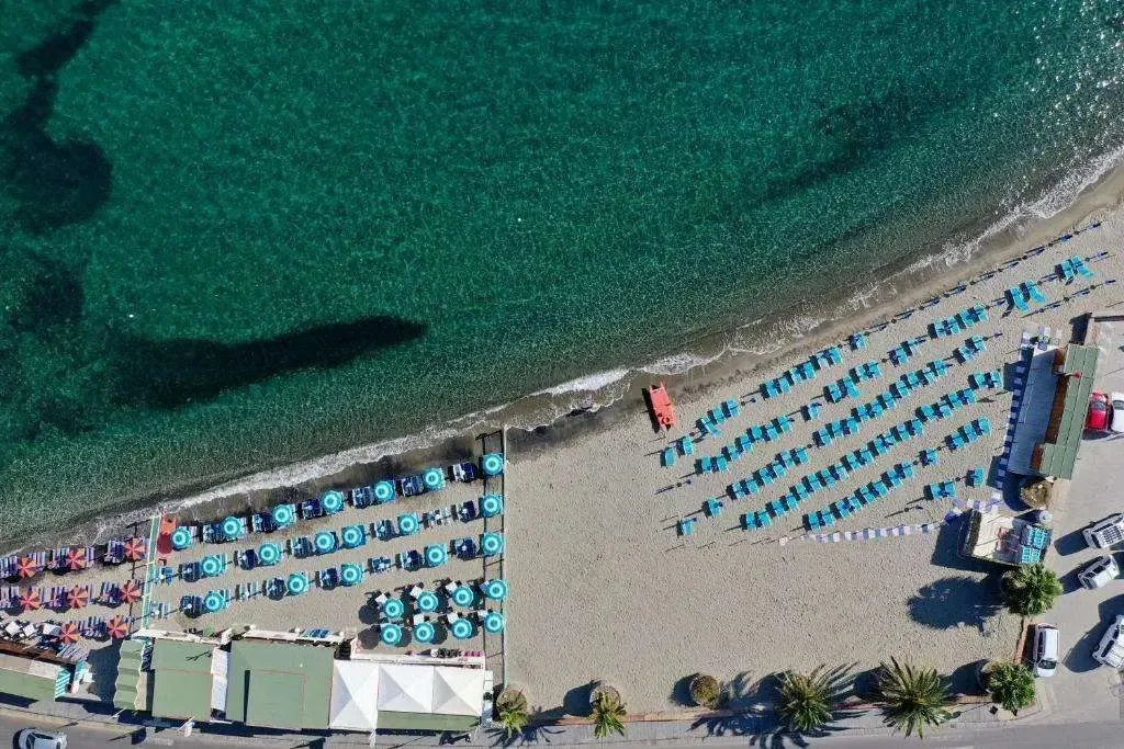 Vista aerea di una spiaggia sabbiosa con ombrelloni colorati e mare turchese