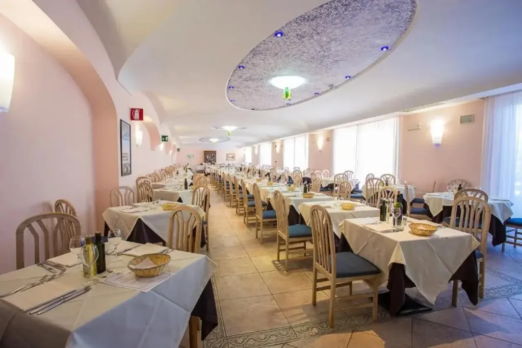 Sala ristorante interna con tavoli apparecchiati con tovaglie bianche e soffitto decorato