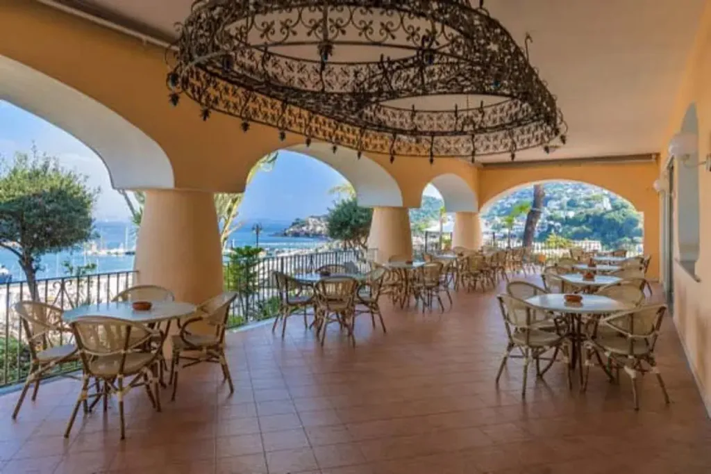 Terrazza con archi, tavoli e sedie in vimini e vista sul mare e sulla costa