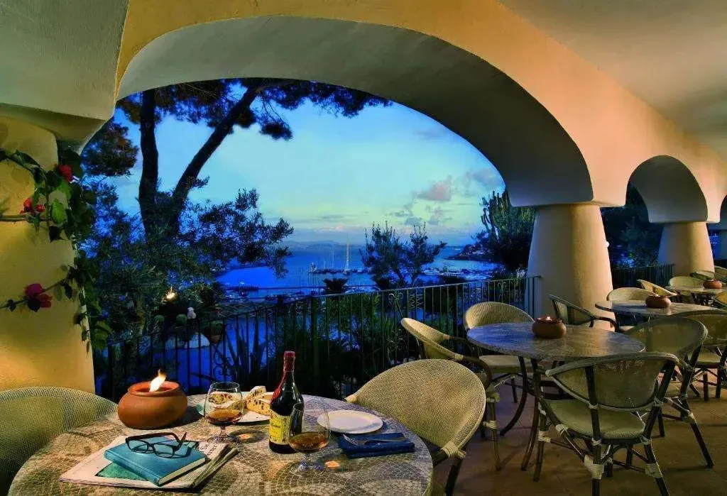 Terrazza al tramonto con tavolo apparecchiato, candele e vista panoramica sul mare e sul porto