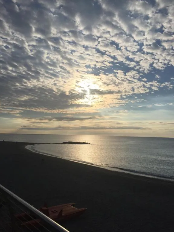 Vista sulla spiaggia e sul mare al tramonto con cielo nuvoloso e riflessi del sole sull'acqua