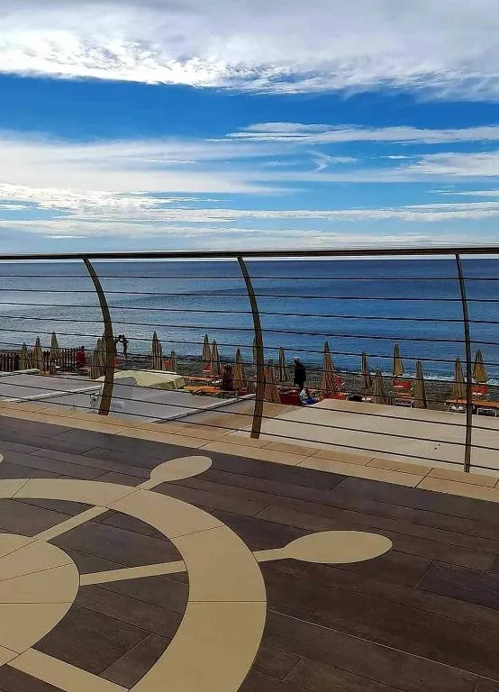 Terrazza panoramica con ringhiera e vista sulla spiaggia con ombrelloni e mare azzurro