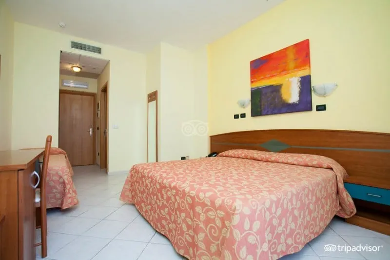 Camera matrimoniale con copriletto rosa e quadro colorato sopra il letto