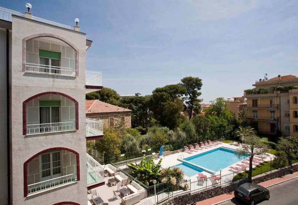 Vista esterna dell'hotel con piscina, lettini e giardini circostanti