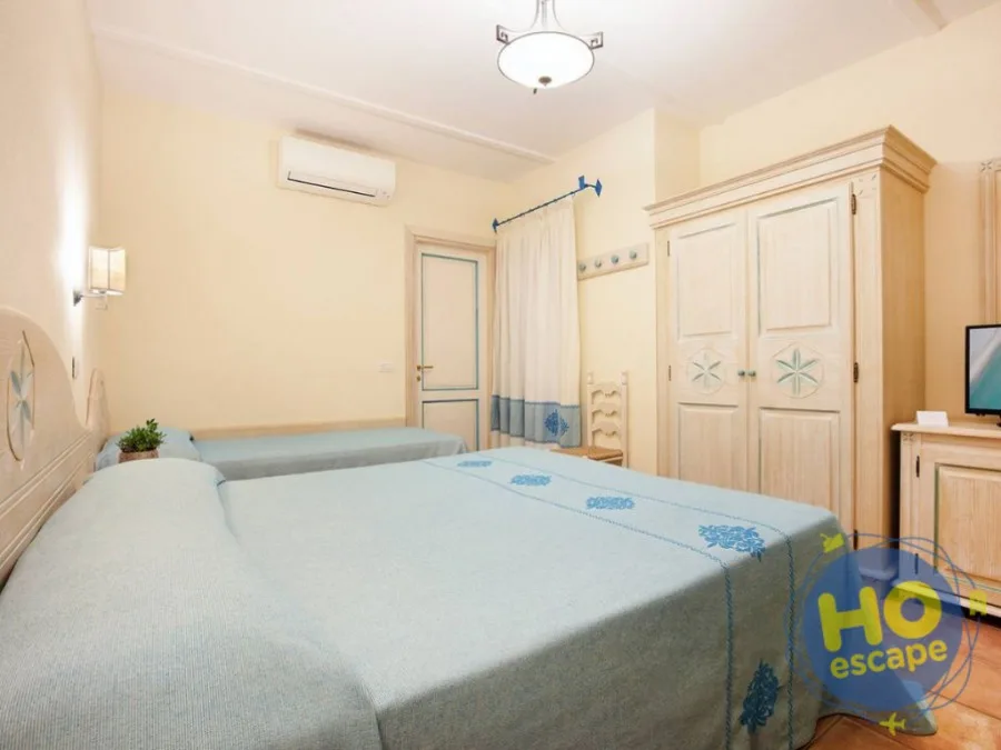 Camera con letto matrimoniale, biancheria azzurra ricamata e armadio in legno chiaro