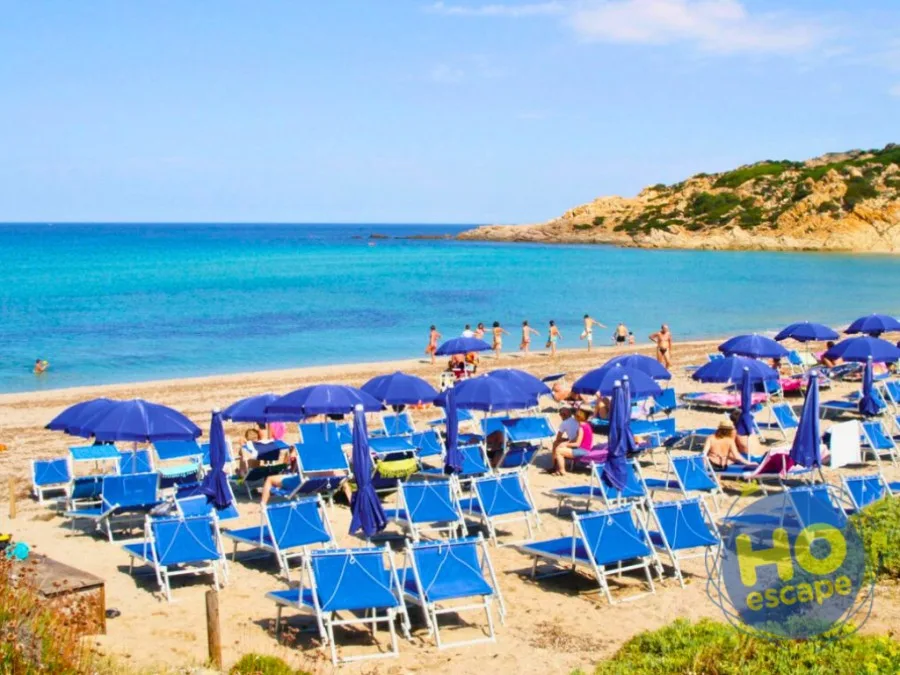Spiaggia sabbiosa con ombrelloni e lettini blu davanti al mare turchese