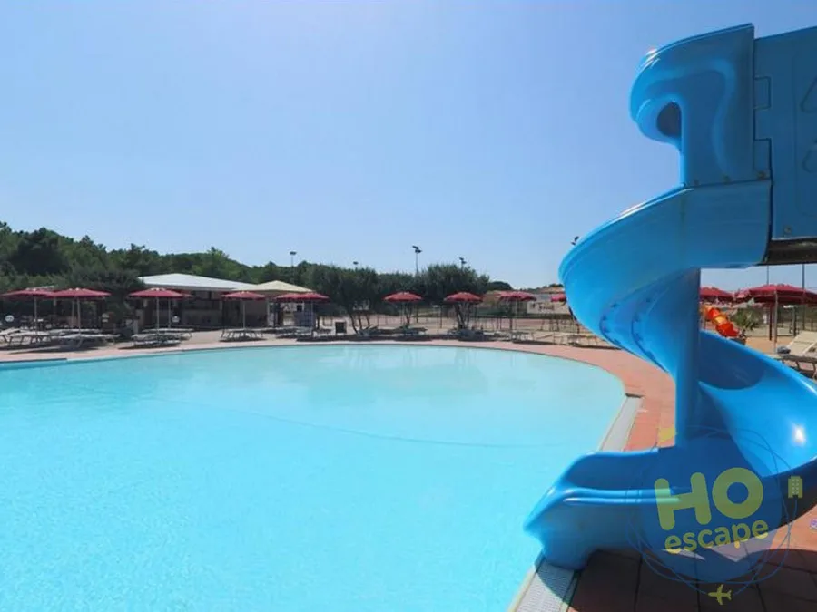 Piscina con scivolo a spirale blu e ombrelloni rossi
