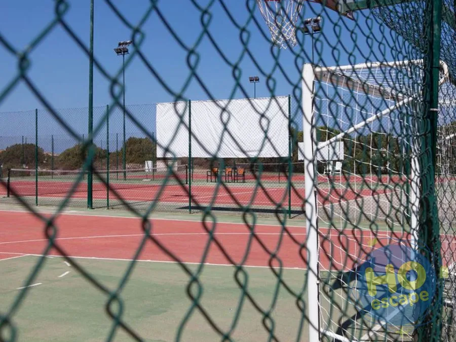 Campi sportivi del villaggio con canestro da basket e porta da calcio dietro recinzione