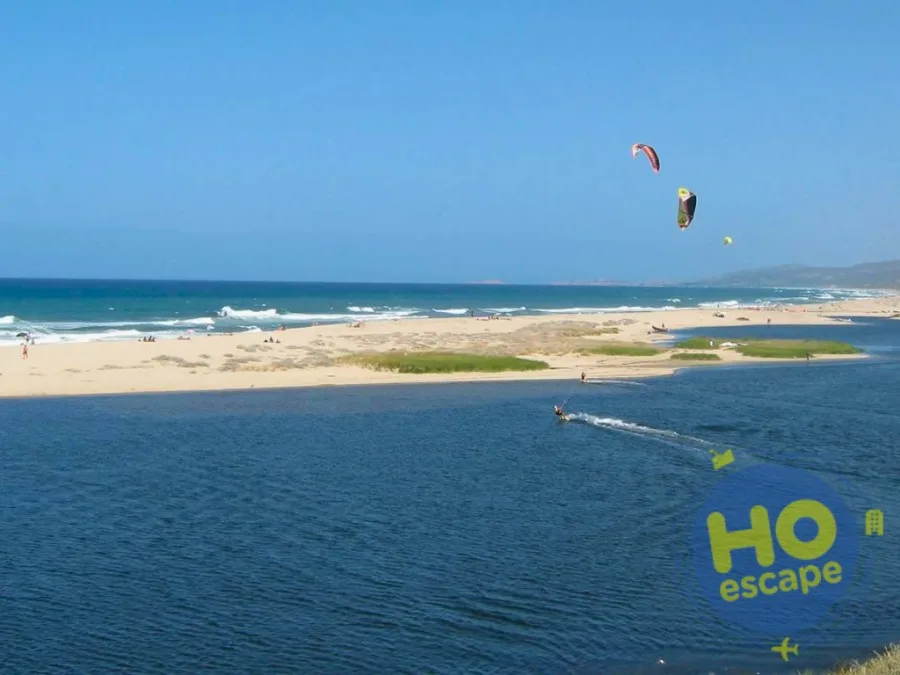 Spiaggia con foce, kitesurf in azione e aquiloni colorati nel cielo