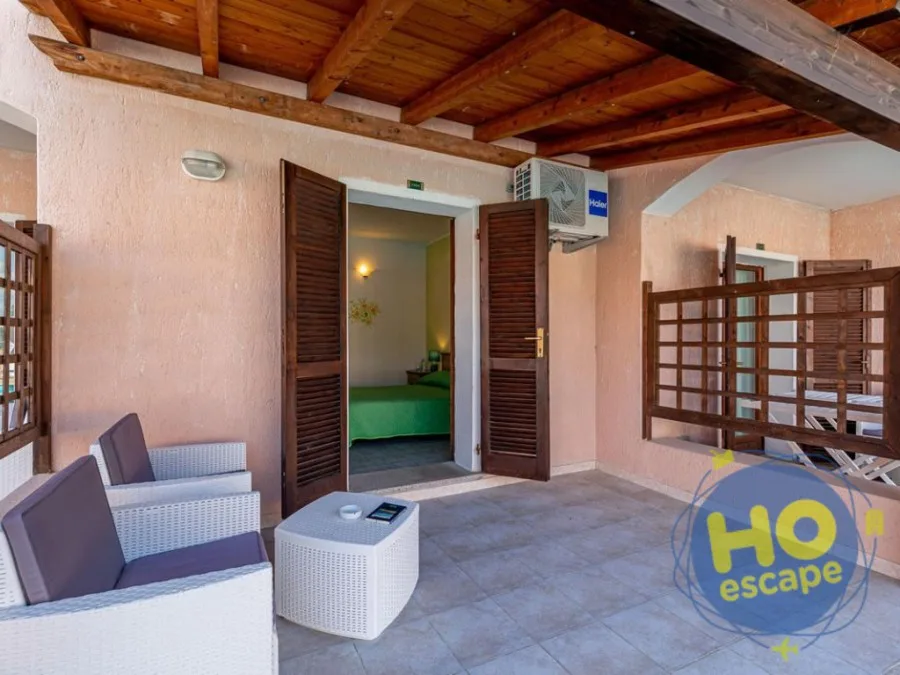 Patio coperto con poltrone in rattan e ingresso alla camera da letto