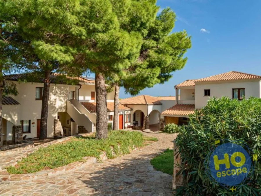 Vialetto in pietra tra le villette bianche del resort ombreggiato da pini marittimi