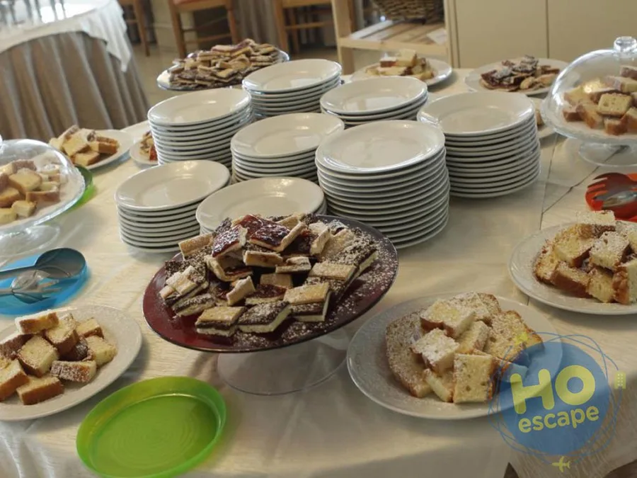Buffet di dolci con fette di torta, crostate e piatti bianchi impilati