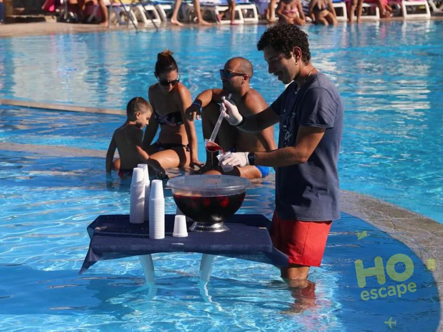 Animatore prepara sangria a bordo piscina servendo gli ospiti in acqua