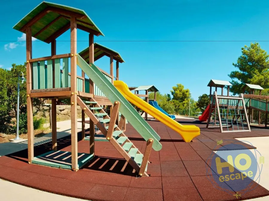 Parco giochi per bambini con scivoli colorati e strutture in legno su pavimento antitrauma