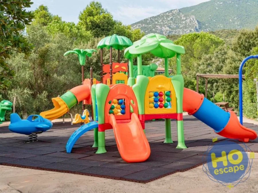 Area giochi colorata per bambini con scivoli e giochi a molla immersa nel verde e tra le montagne