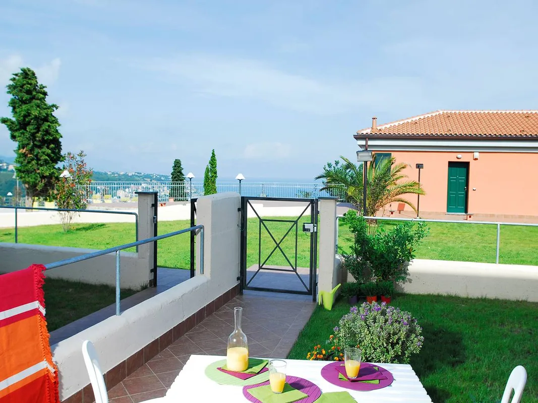 Terrazza esterna con tavolo apparecchiato, giardino e vista mare