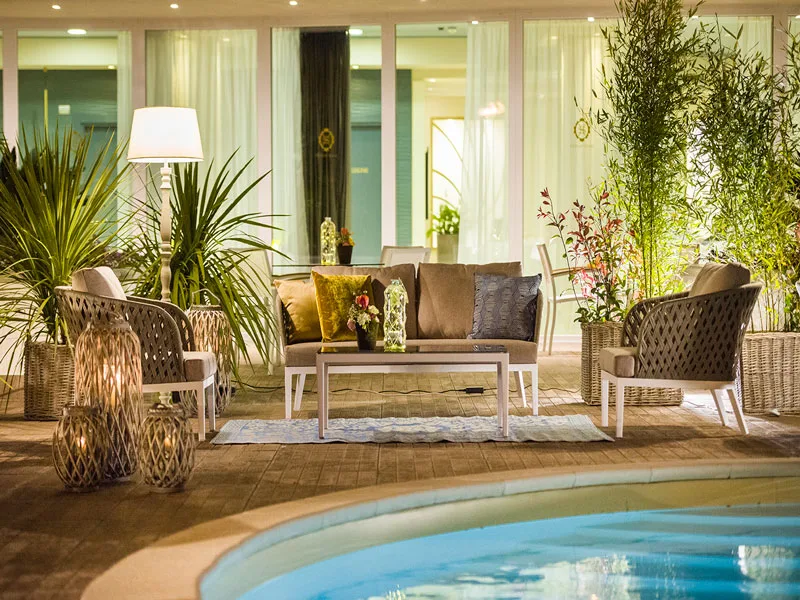 Salottino esterno con poltrone in rattan e lanterne vicino alla piscina