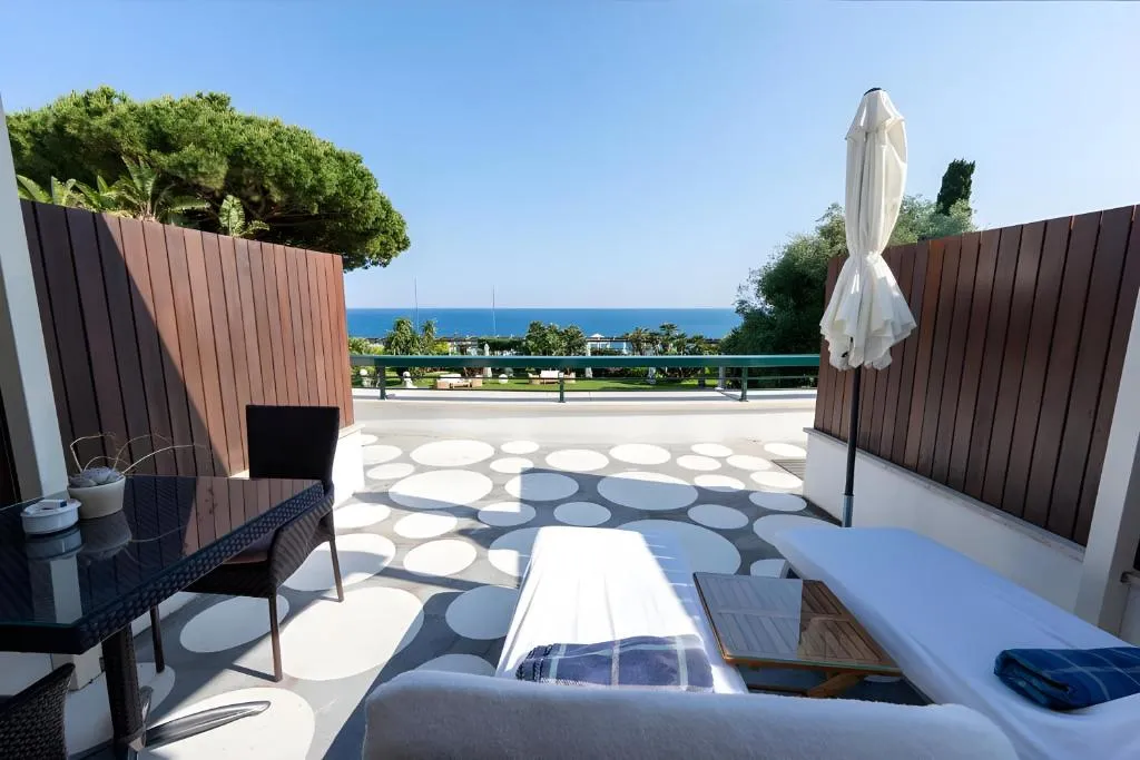 Terrazza privata con lettino, ombrellone e tavolino affacciata su giardino e mare