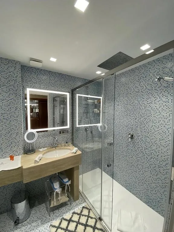 Bagno moderno con doccia in vetro, mosaico grigio e specchio illuminato