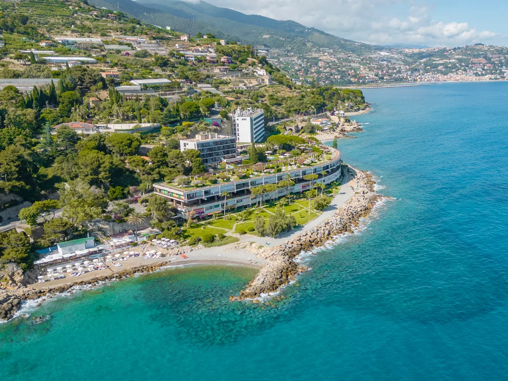 Panorama aereo dell'hotel sulla costa ligure con spiaggia, mare cristallino e colline sullo sfondo