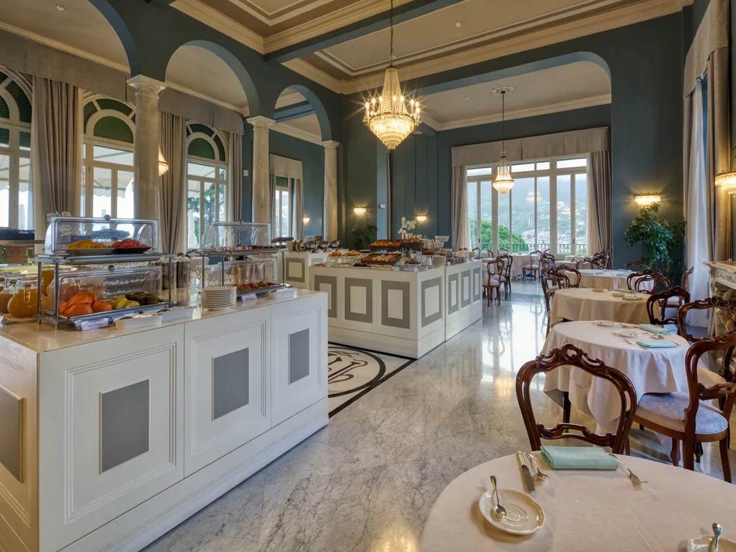 Sala colazione elegante con buffet, lampadari di cristallo e pareti color verde-azzurro