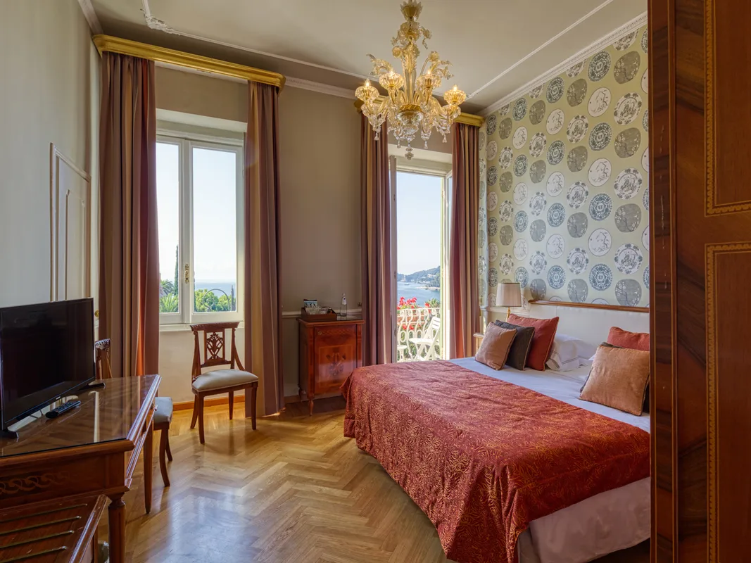 Camera classica con letto matrimoniale, lampadario di Murano, carta da parati decorata e vista mare