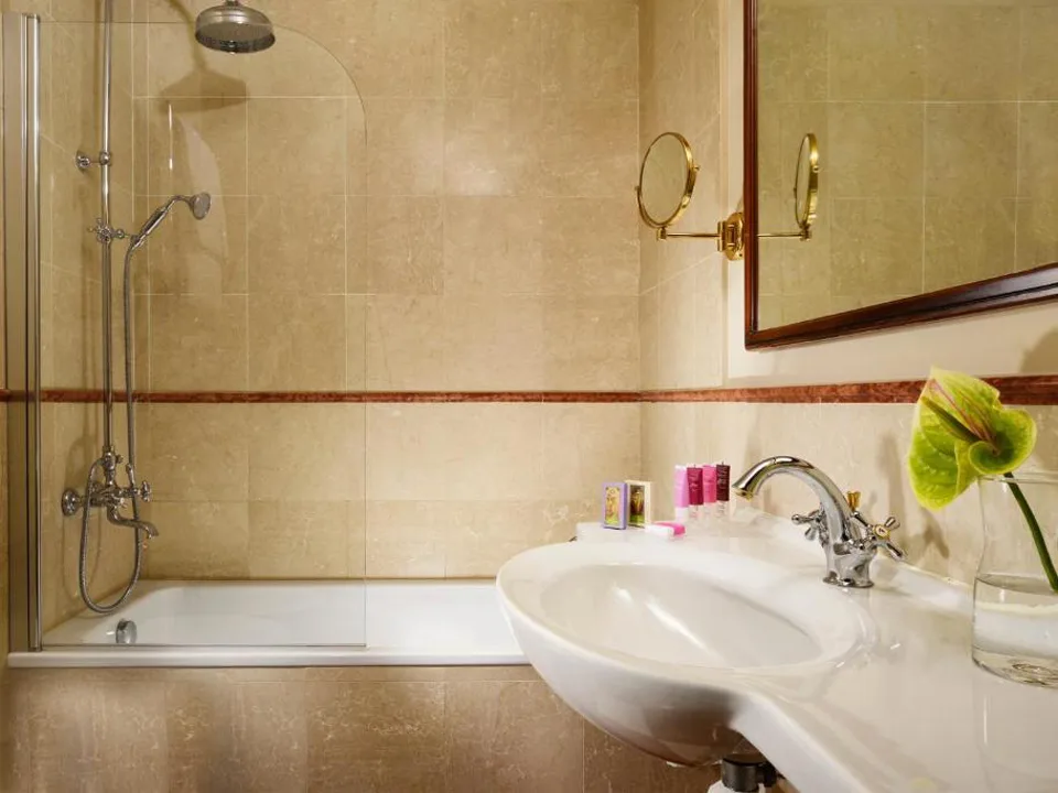 Bagno con vasca decorata, doccia e lavabo con fiore verde