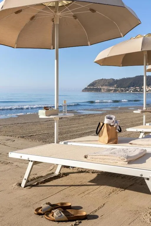 Lettino con ombrellone sulla spiaggia di sabbia con vista sul mare e promontorio