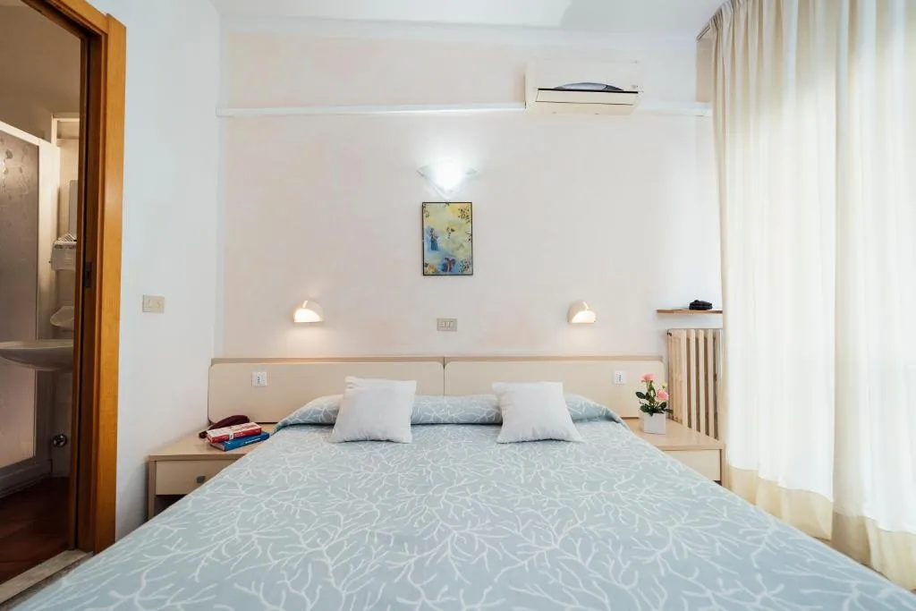 Letto matrimoniale con cuscini bianchi e accesso al bagno