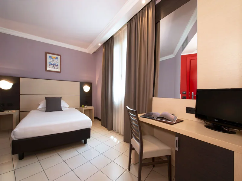 Camera singola con letto, scrivania, sedia e televisore