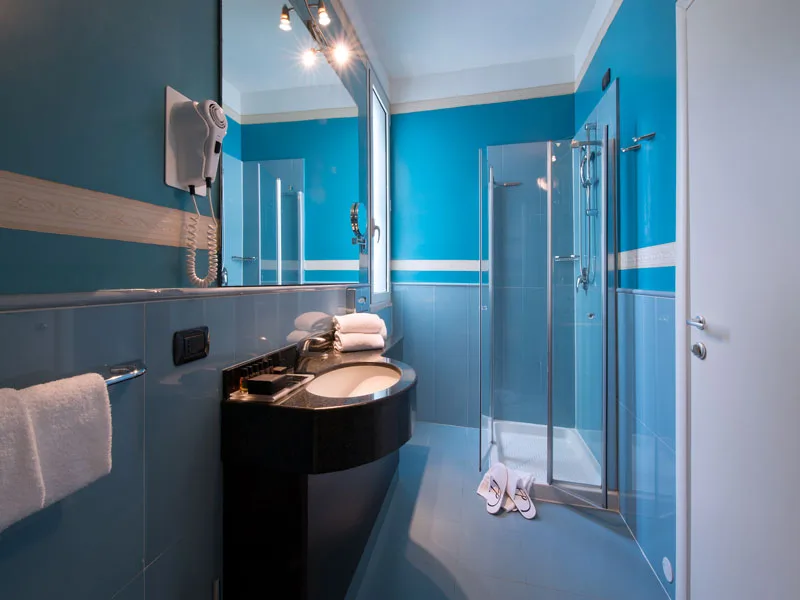 Bagno moderno azzurro con lavabo nero, grande specchio e doccia