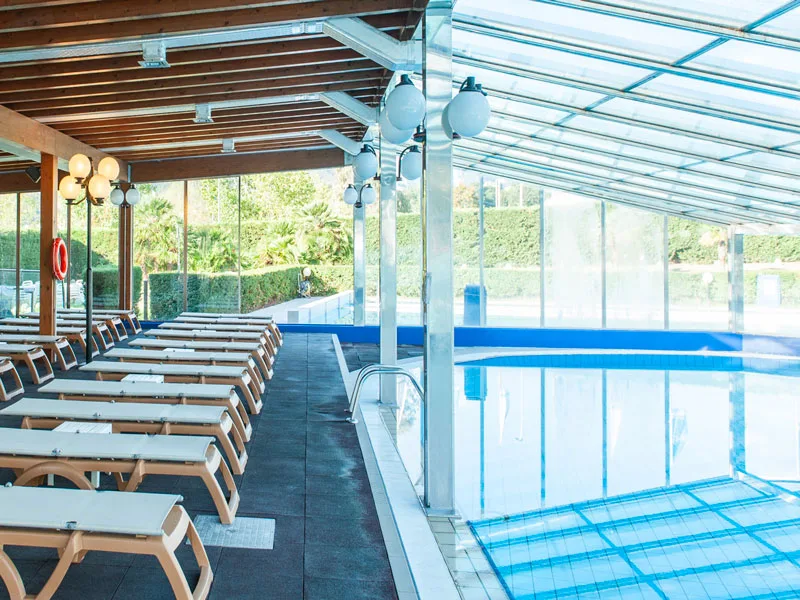 Piscina coperta con lettini allineati e copertura in vetro