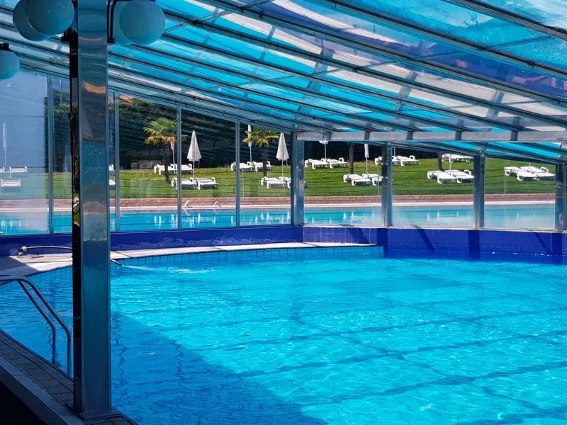 Piscina coperta con struttura in vetro e vista sul giardino