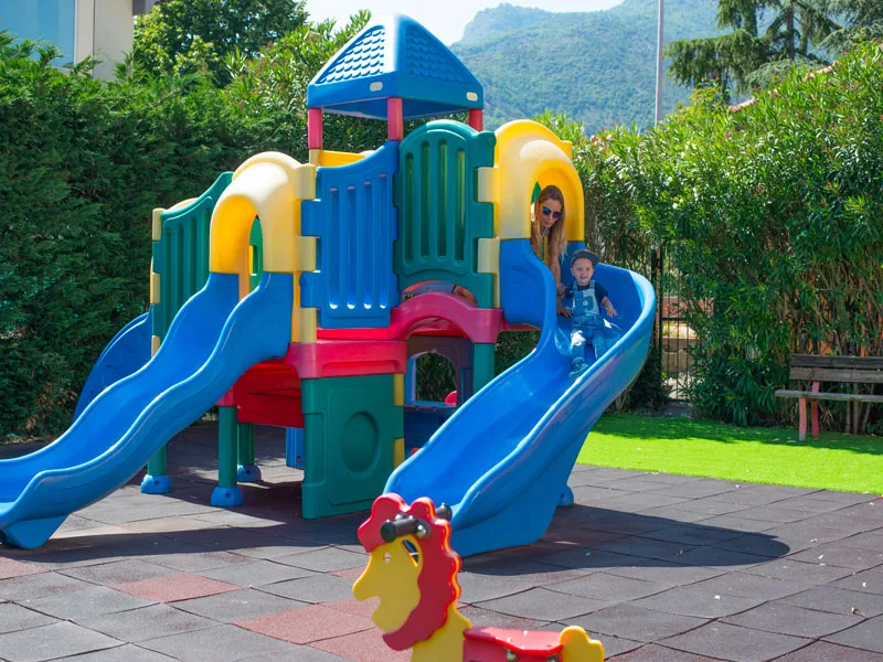 Area giochi per bambini con scivoli colorati e mamma con bimbo