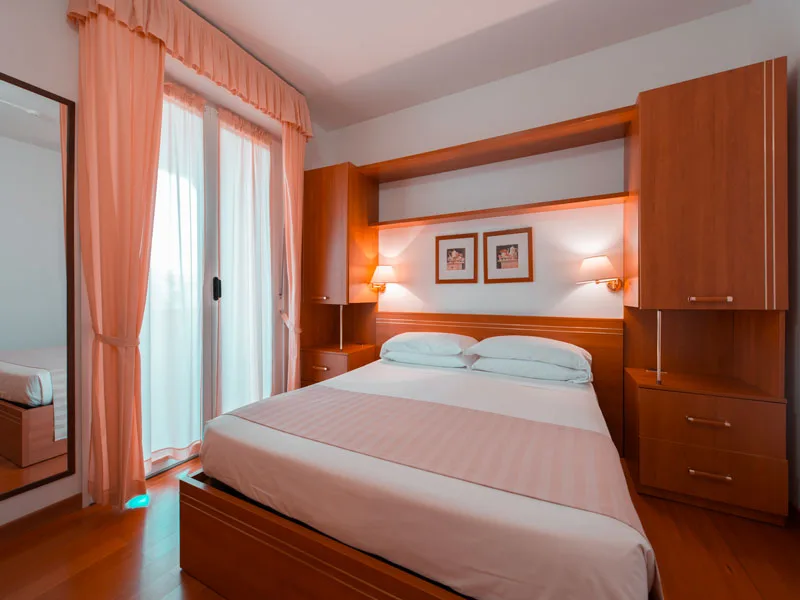 Camera da letto matrimoniale con arredo in legno e tende rosa