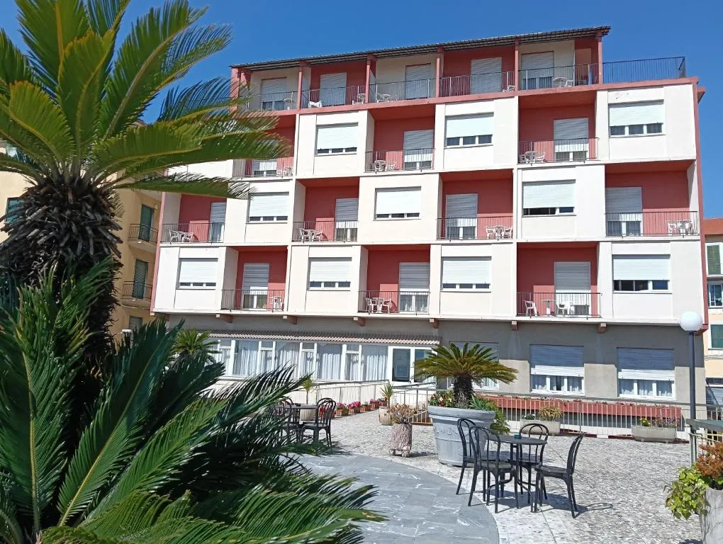 Facciata dell'hotel con balconi, palme e terrazza esterna