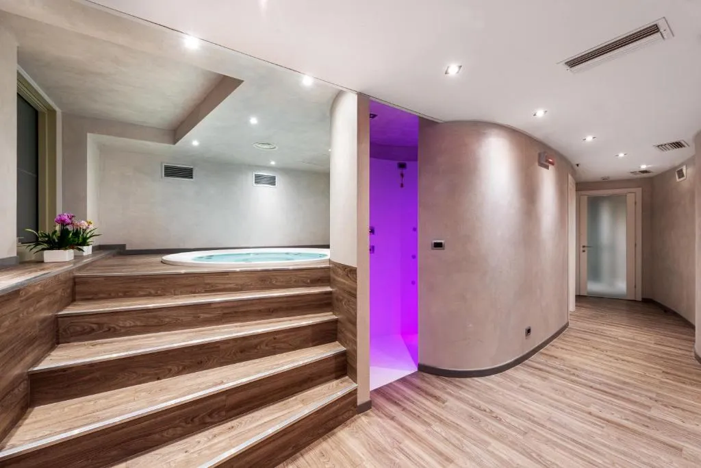 Area spa con vasca idromassaggio rialzata, gradini in legno e illuminazione viola