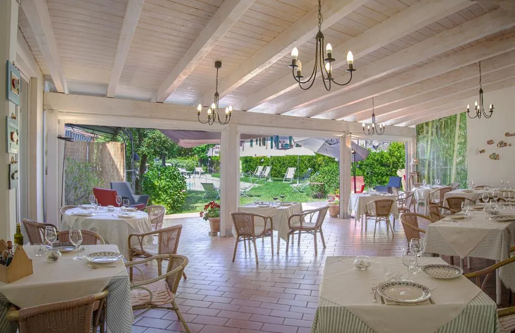 Sala ristorante con tavoli apparecchiati affacciata sul giardino