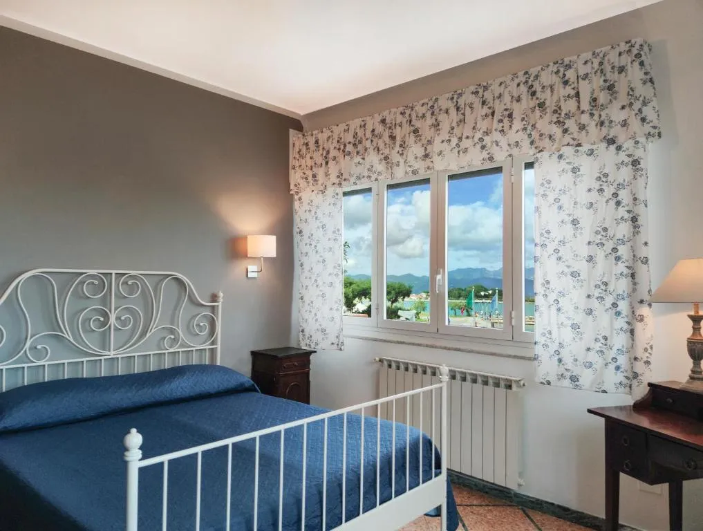 Camera con letto in ferro blu e finestra con vista sulle colline