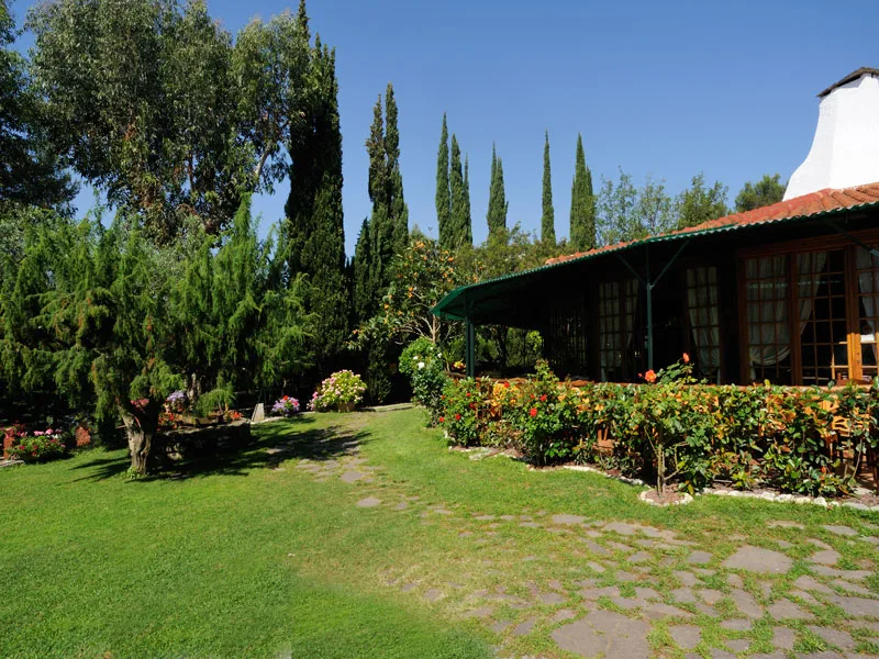 Giardino curato con prato, fiori colorati e veranda coperta del ristorante