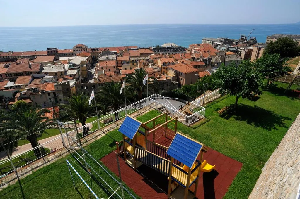 Area giochi per bambini con scivolo all'aperto e vista panoramica sui tetti della cittadina e sul mare