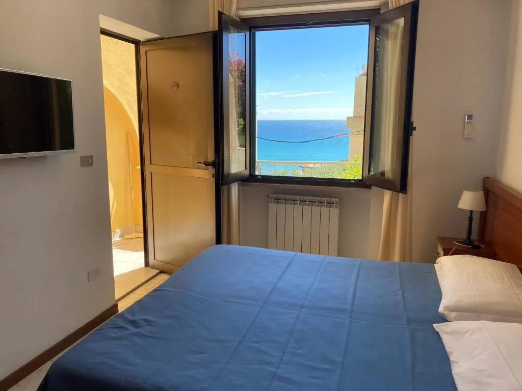 Camera matrimoniale con TV e finestra aperta con vista sul mare