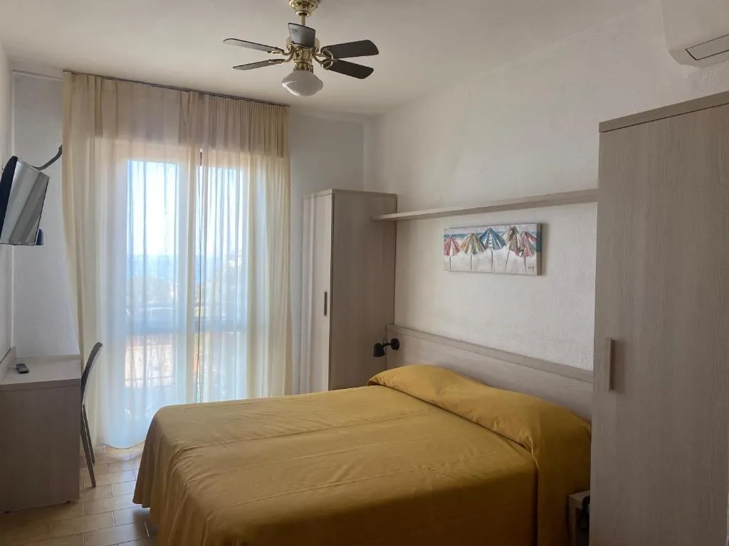 Camera con letto giallo, ventilatore a soffitto e finestra luminosa