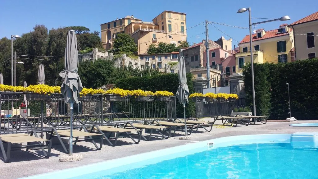 Bordo piscina con lettini e ombrelloni, panorama sul borgo storico in collina