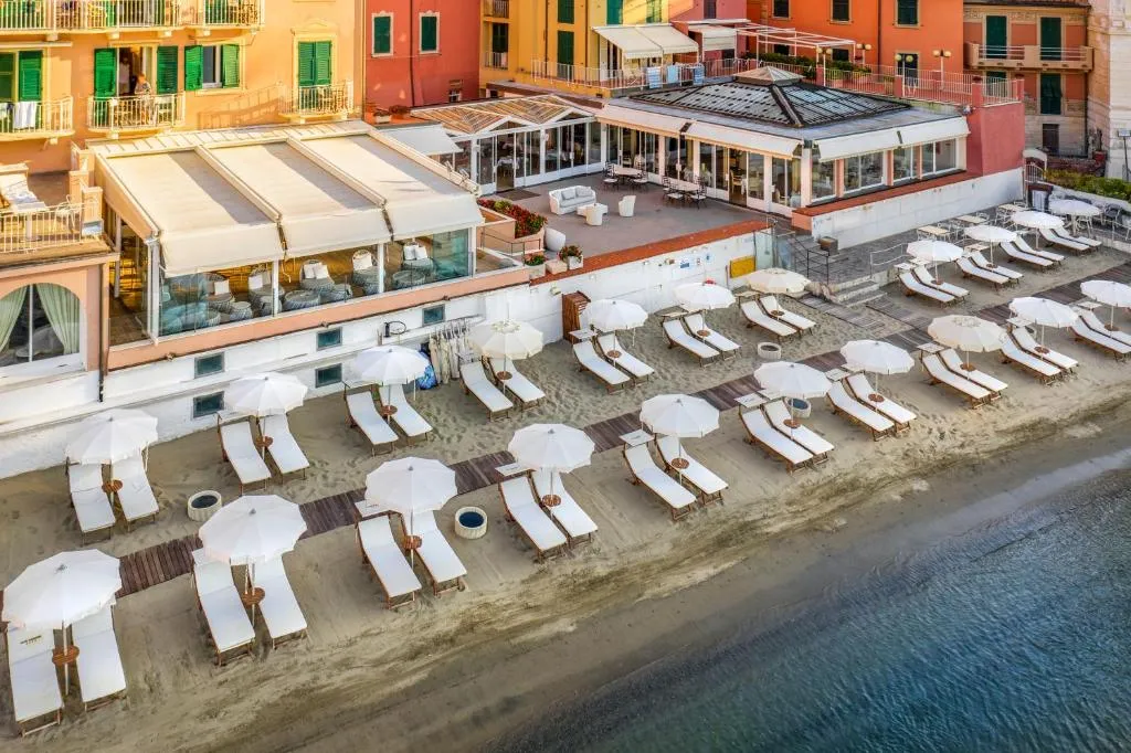 Vista aerea della spiaggia privata con lettini bianchi, ombrelloni e terrazza del ristorante