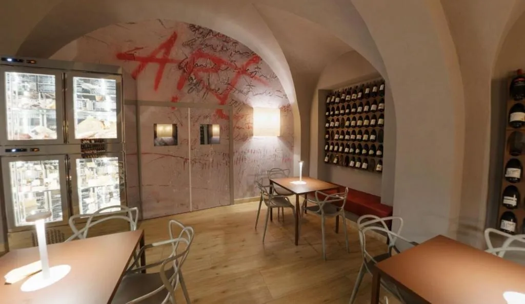 Sala degustazione con volte in pietra, tavoli e cantina di vini a parete