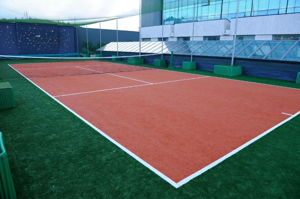 Campo da tennis in terra rossa all'aperto accanto all'edificio dell'hotel