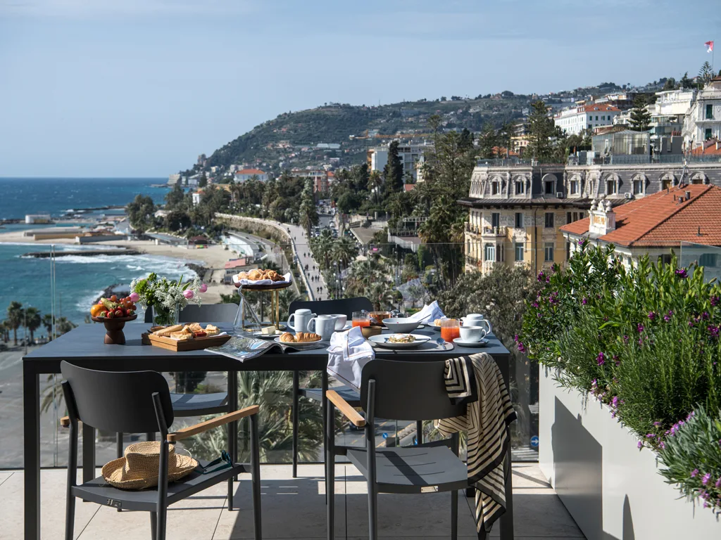 Terrazza con tavolo colazione e vista sul lungomare, la spiaggia e gli edifici storici di Sanremo