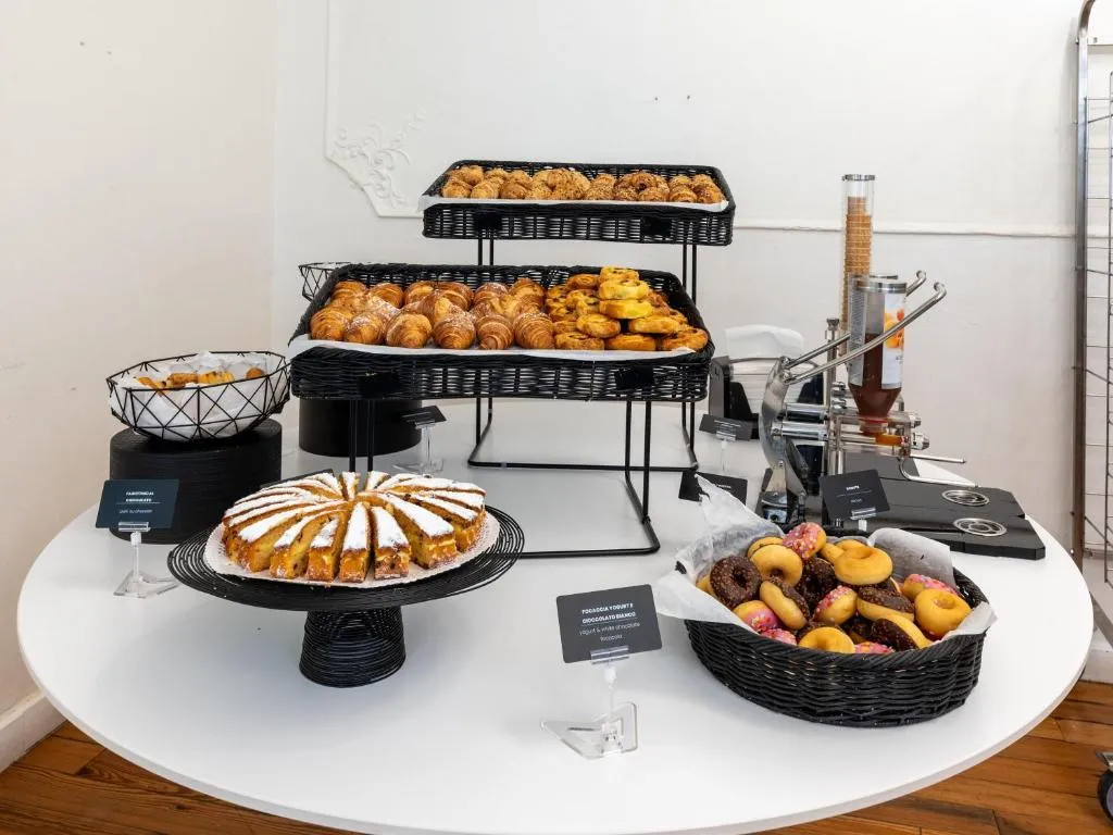 Buffet della colazione con cornetti, dolci, ciambelle glassate e torta su tavolo rotondo bianco